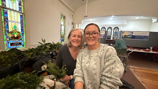 Two participants enjoying the fresh holiday greens wreath workshop