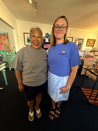 **Shopify Photo Description (Alt Text):**

Two women modeling Solomons, Maryland embroidered short-sleeve t-shirts inside Savvie's Blue Shell Boutique. One wears a slate gray tee with navy shorts and white sandals, while the other wears a bright blue tee paired with a light blue patterned skirt and black sandals. The coastal-inspired embroidered flag logo is featured on the left chest of each shirt, showcasing comfortable everyday style and hometown pride.
 