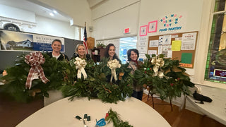 Four workshop participants holding their finished fresh evergreen wreaths at Solomons Mission Center