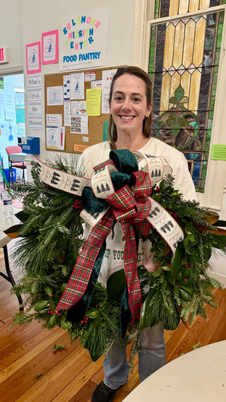 Holiday greens wreath workshop — participant holding a finished wreath